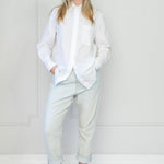 Person wearing a white blouse and light blue pants against a white background