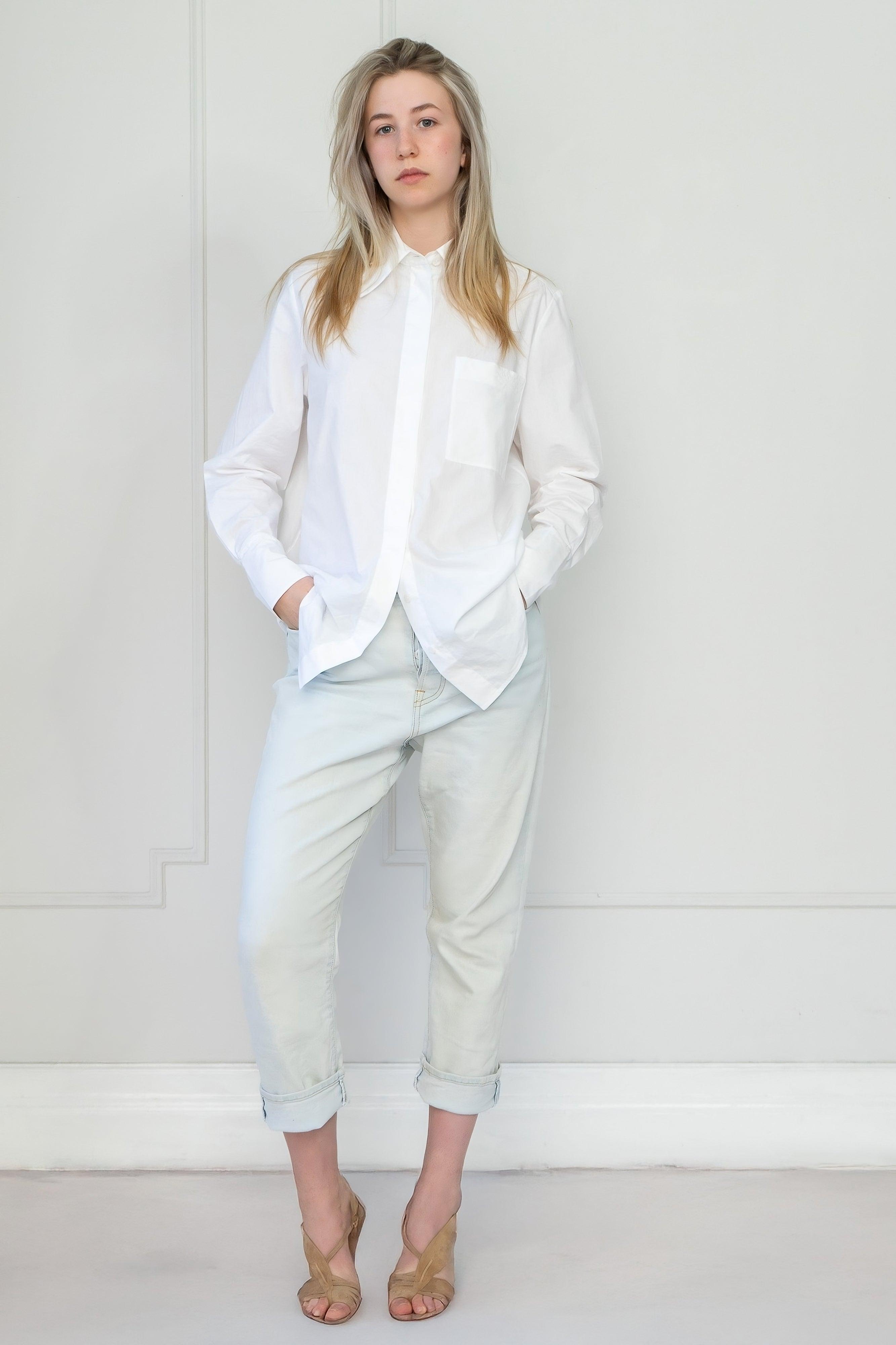 Person wearing a white blouse and light blue pants against a white background