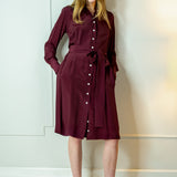Woman wearing a burgundy dress with a belt against a white wall - dress by Room502
