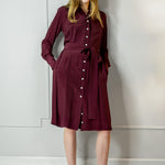 Woman wearing a burgundy dress with a belt against a white wall - dress by Room502