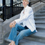 Person wearing a white shirt and blue jeans sitting on stone steps.