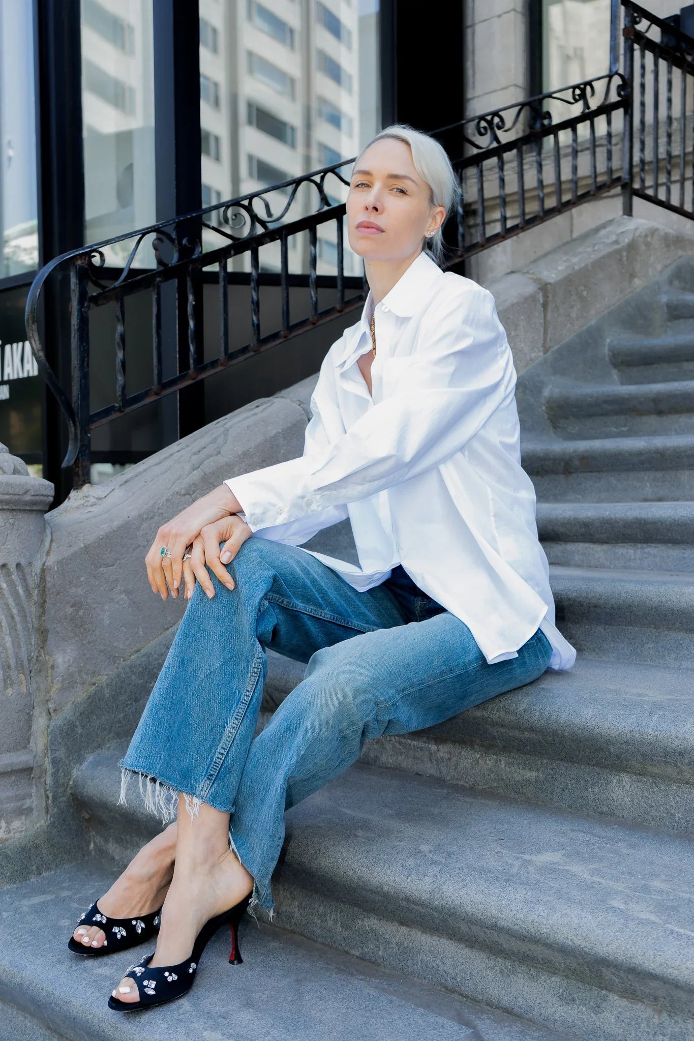 Person wearing a white shirt and blue jeans sitting on stone steps.