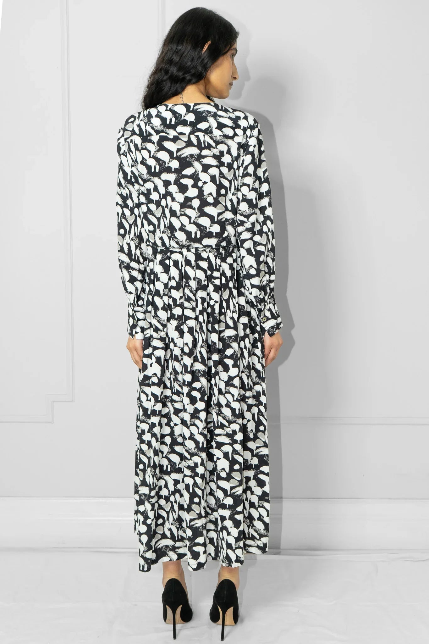 Woman wearing a black and white patterned dress against a plain background