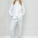 Person wearing a white blouse and light blue pants against a white background