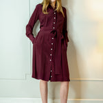 Woman wearing a burgundy dress with a belt against a white wall - dress by Room502