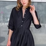 Woman wearing a black shirtdress with a blurred background