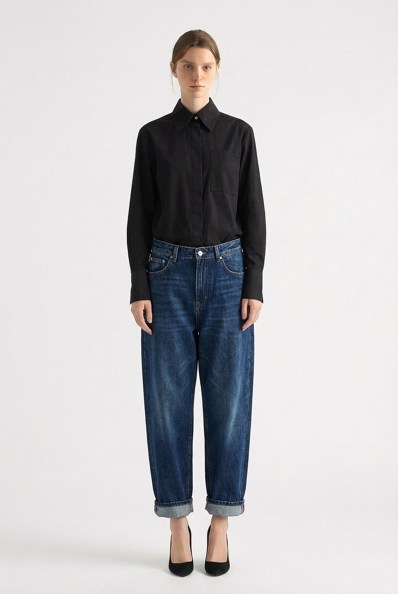 Person wearing a black shirt and blue jeans on a white background