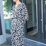 Woman in a black and white patterned dress standing outside a building.