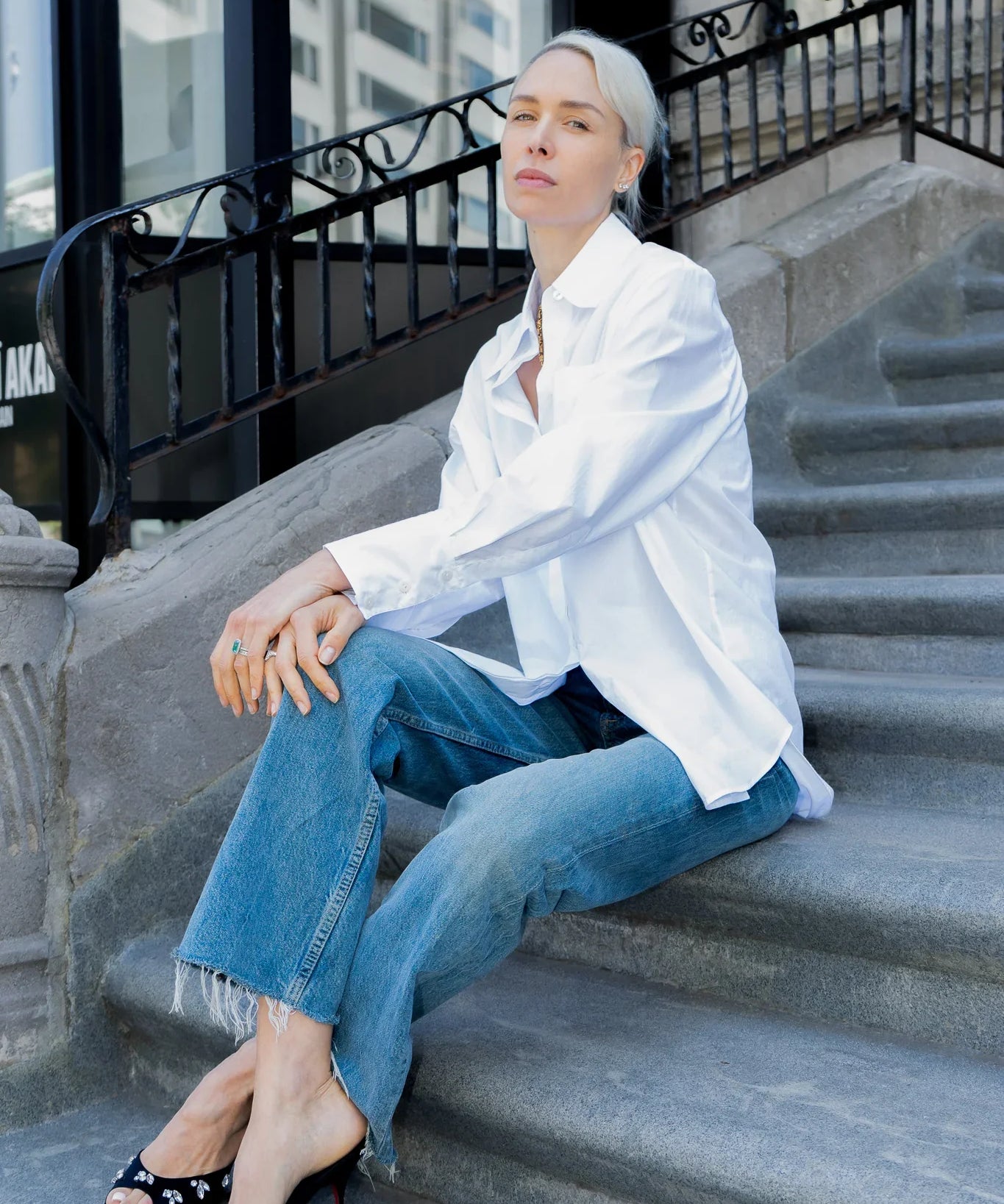 Person wearing a white shirt and blue jeans sitting on stone steps.