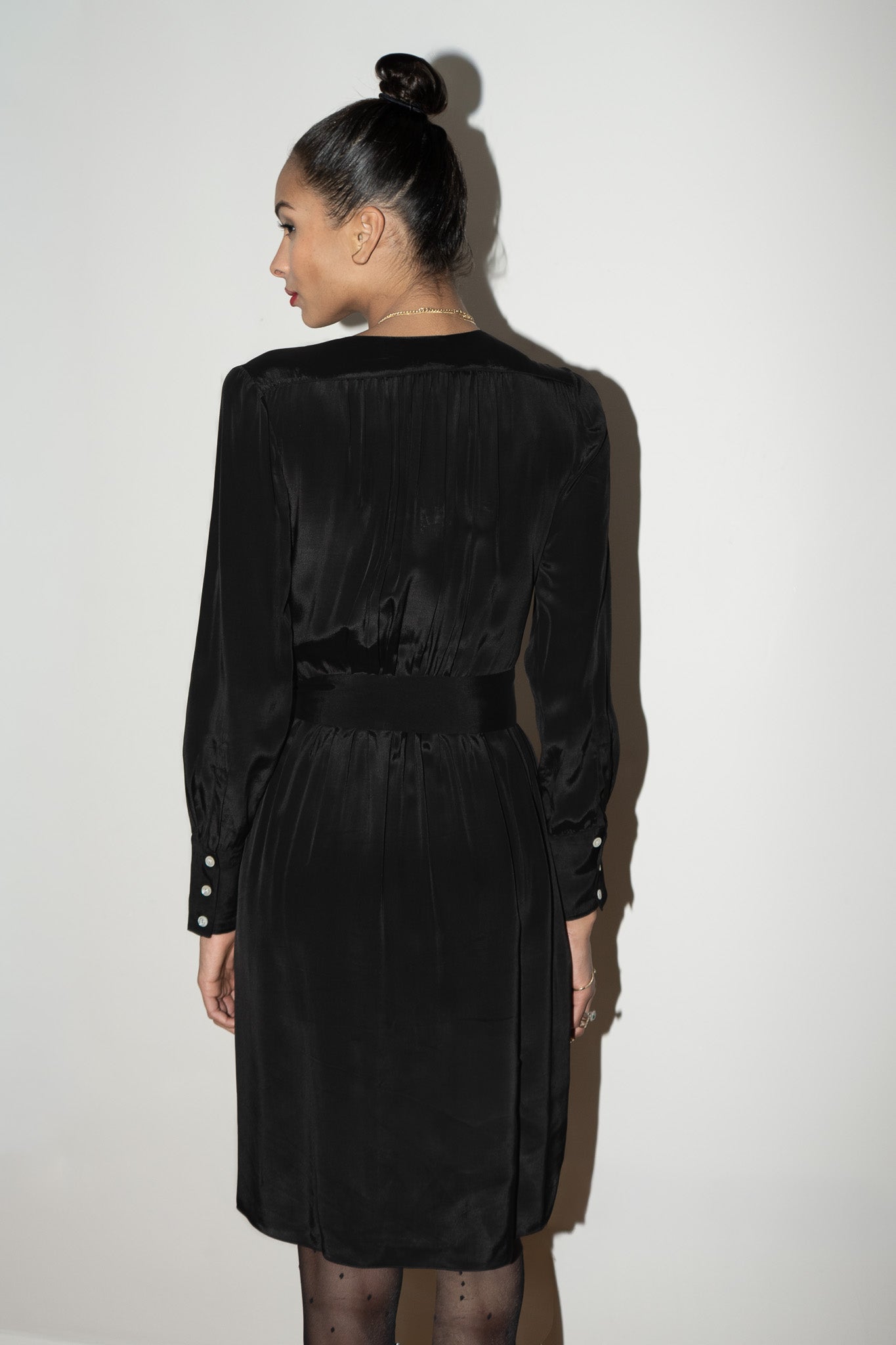 Woman wearing a black silk dress against a white background