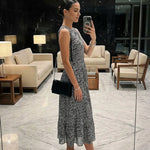 Woman taking a selfie in a stylish dress and high heels in a modern interior setting.