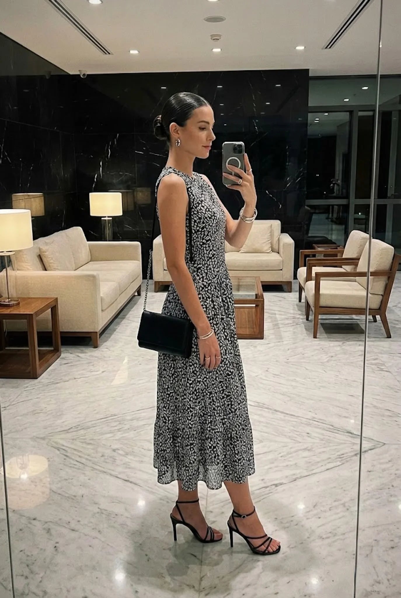 Woman taking a selfie in a stylish dress and high heels in a modern interior setting.