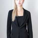 Woman wearing a black suit outfit against a plain background
