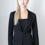 Woman wearing a black suit outfit against a plain background