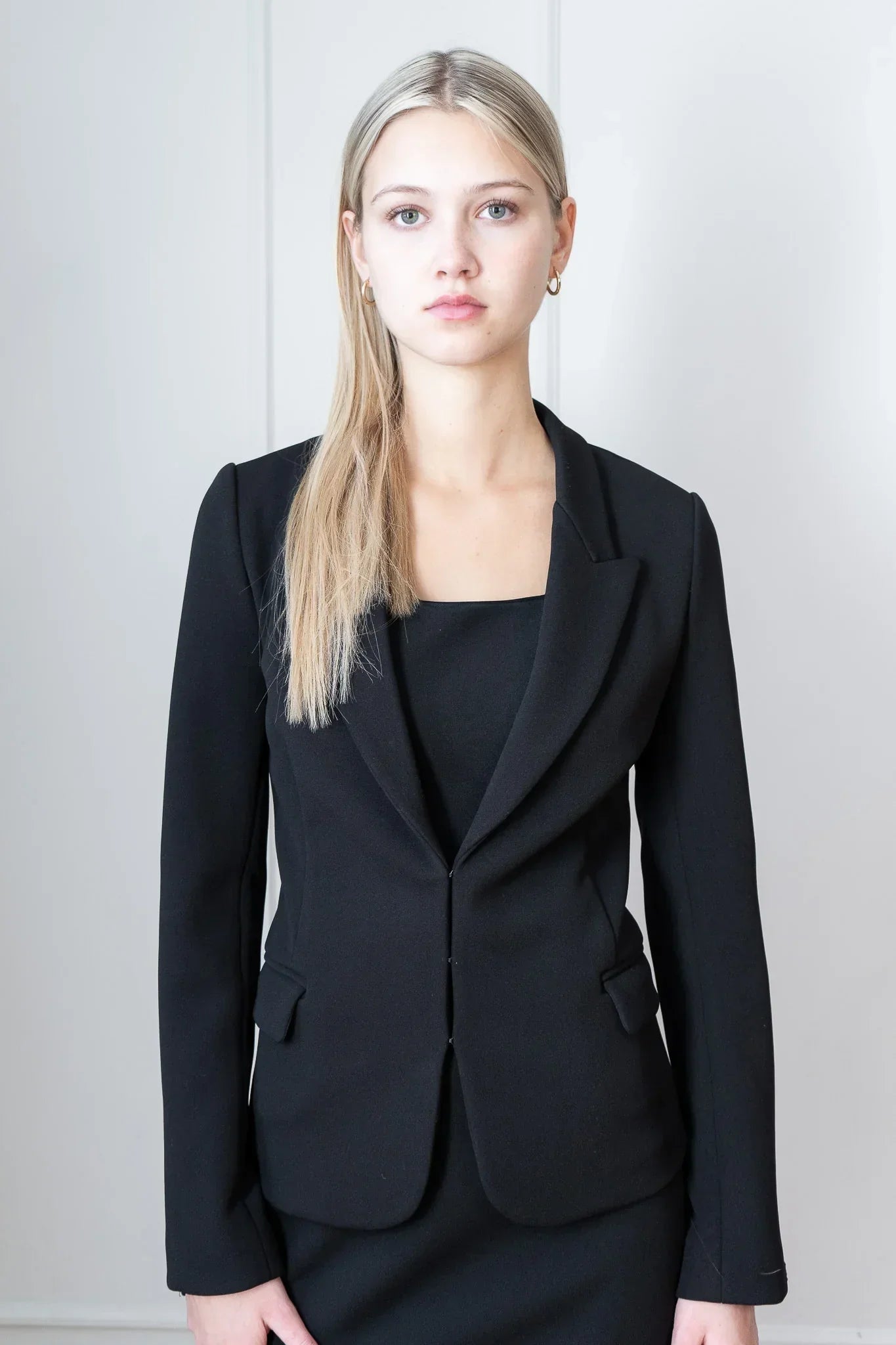 Woman wearing a black suit outfit against a plain background
