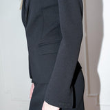 Dark blazer worn by a person against a plain background.