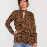 Woman wearing a brown checkered blouse and blue jeans against a white background