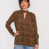 Woman wearing a brown checkered blouse and blue jeans against a white background