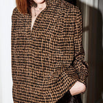 Woman wearing a brown and black checkered shirt with a blurred background