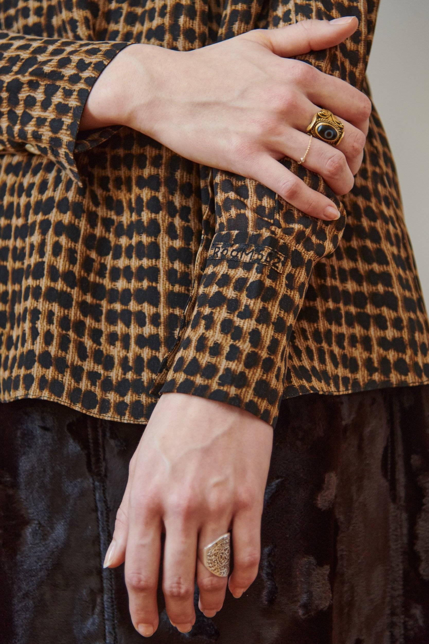 Close-up of hands wearing rings, one with a leopard print sleeve.